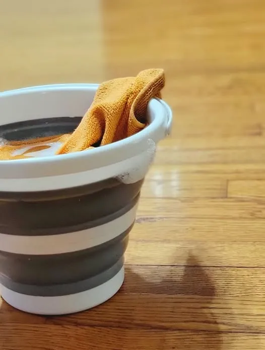 A collapsible mop bucket and cloth on the hardwood floor